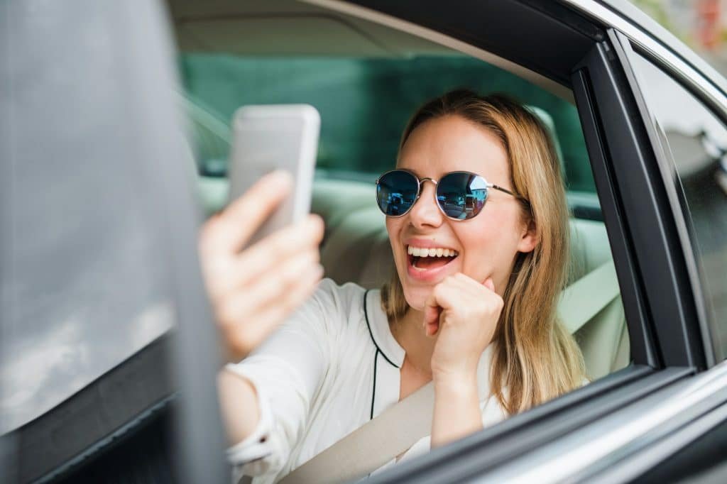 Business woman sitting on back seat in taxi car, taking selfie